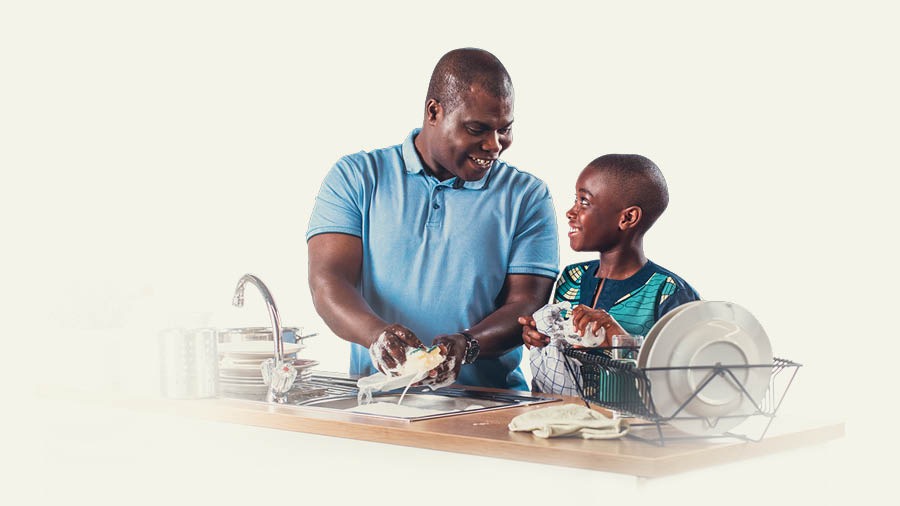 Un padre y su hijo lavan juntos los platos.