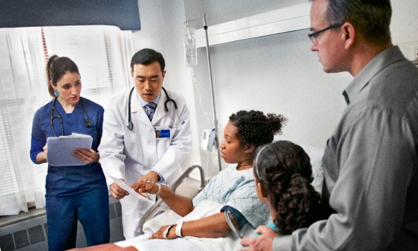 ’n Christensuster in ’n hospitaalbed praat met mediese deskundiges