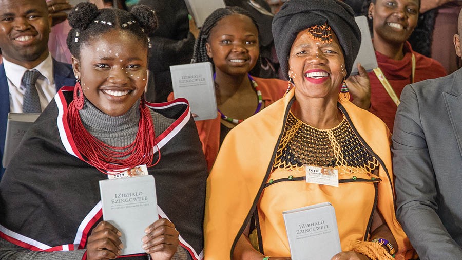 Susters en ’n broer hou die pas vrygestelde ‘Nuwe Wêreld-vertaling’ in Xhosa vas.