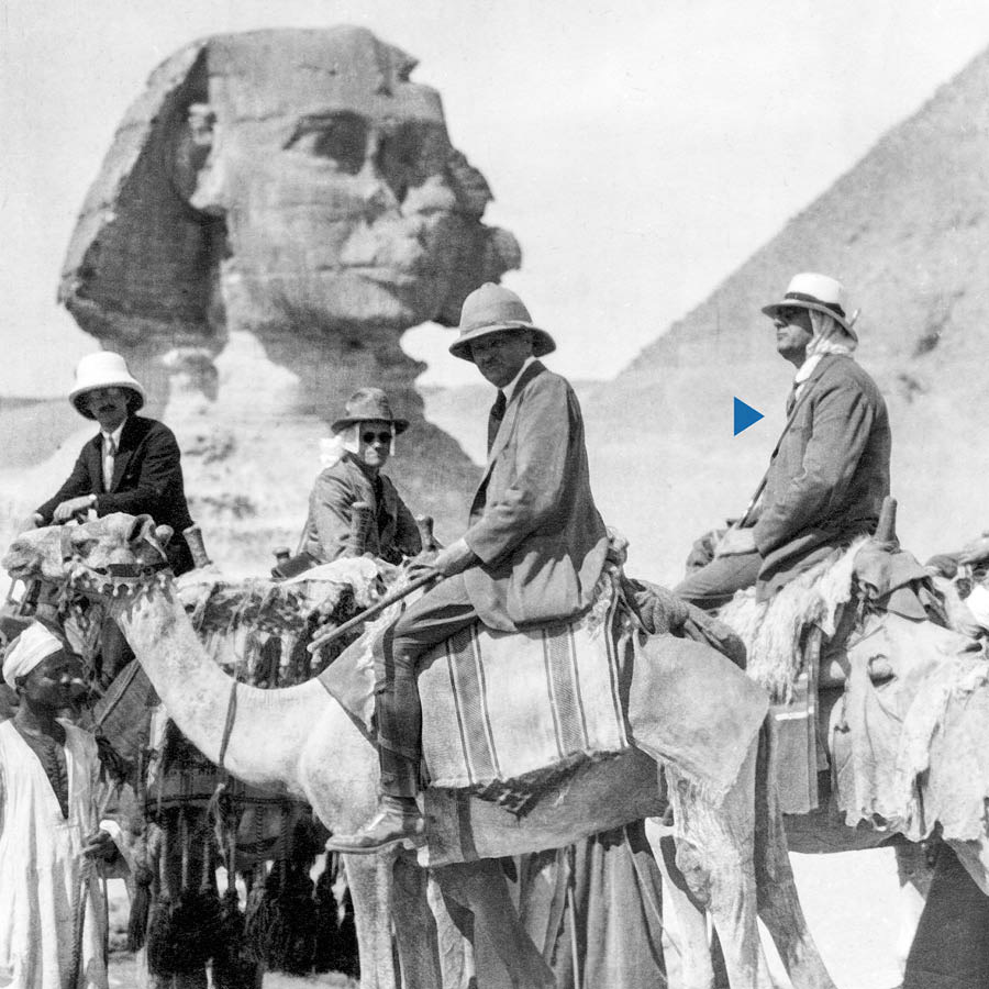 Joseph F. Rutherford en ander broers ry op kamele naby die Groot Sfinks van Giza.