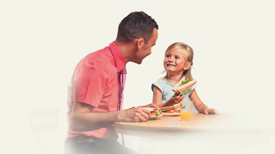 ’n Pa en sy dogtertjie eet ’n toebroodjie saam.