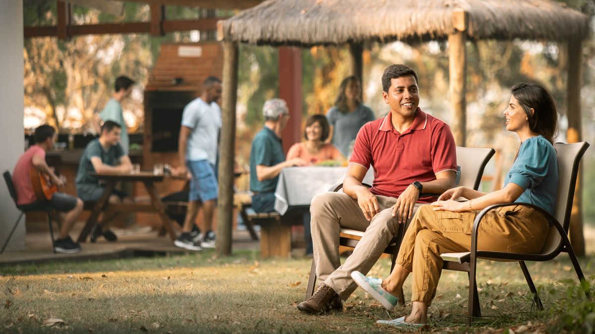 A courting couple sitting together at a social gathering. They are conversing privately with each other.