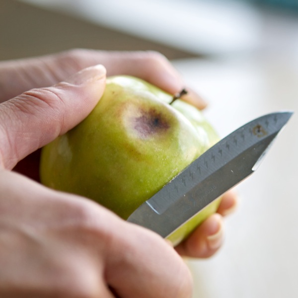 Cutting a rotten spot out of a piece of fruit