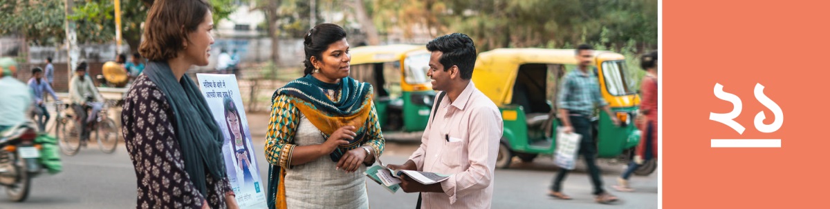 পাঠ ২১। দু-জন যিহোবার সাক্ষি রাস্তার ধারে সাহিত্যের ট্রলির পাশে দাঁড়িয়ে আছেন এবং একজন ব্যক্তির সঙ্গে কথা বলছেন।