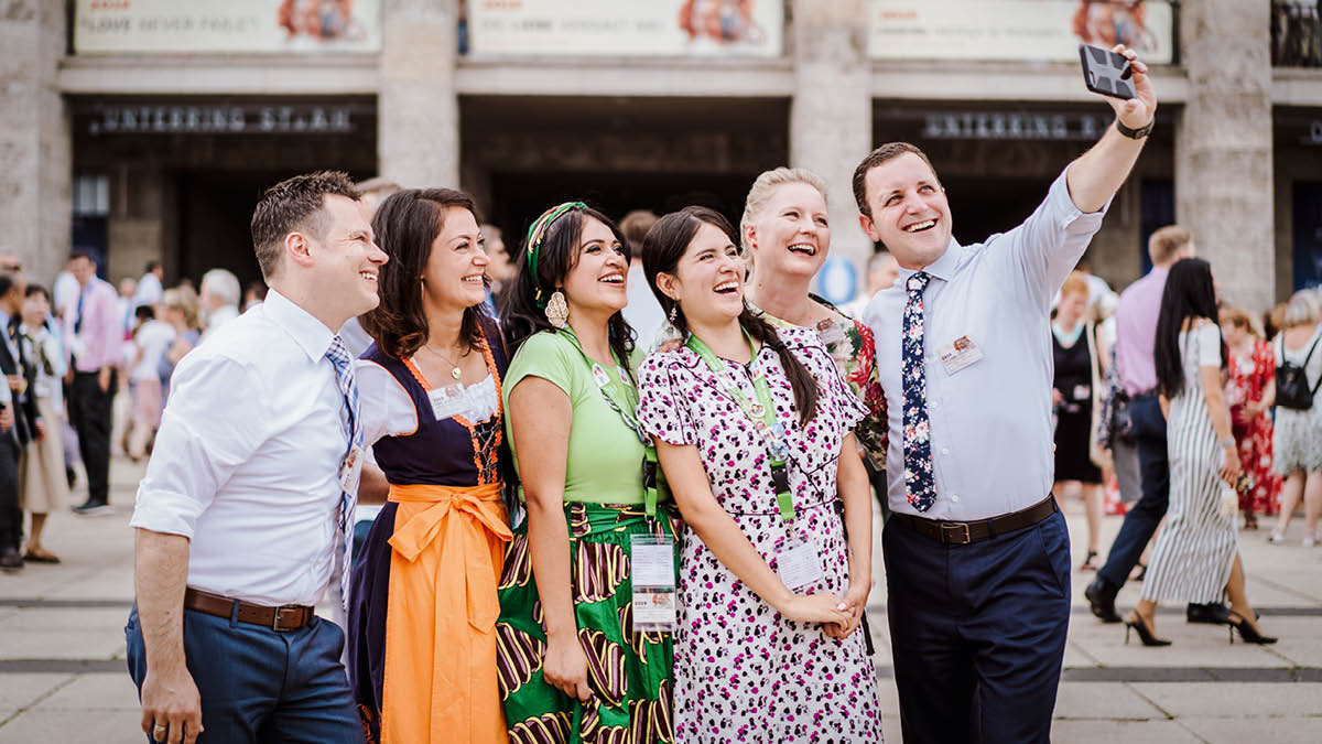 Um grupo de irmãos e irmãs felizes de várias culturas tirando uma foto num congresso.