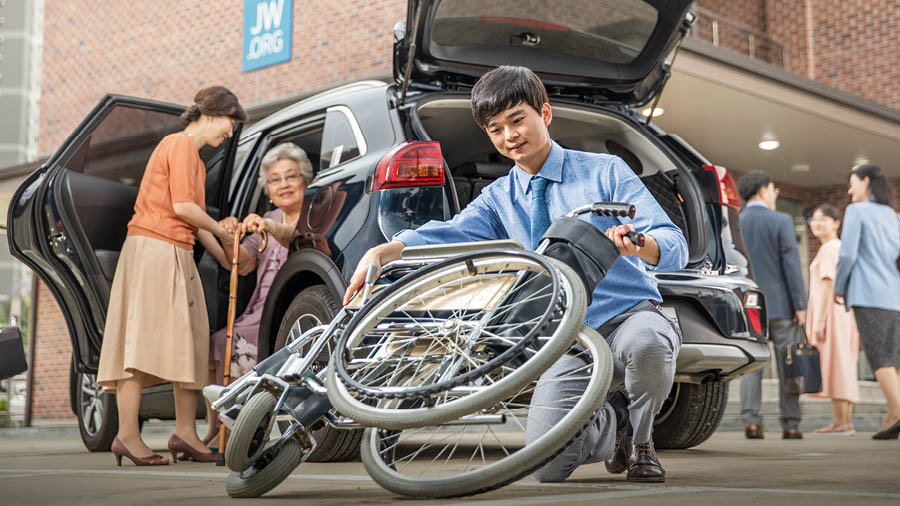 Ang batan-ong brader nagplastar sa wheelchair sa tigulang nga sister samtang gitabangan kini sa iyang mama sa pagkanaog sa sakyanan.