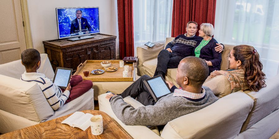 Starší manželé se společně s mladší rodinou dívají na JW Broadcasting