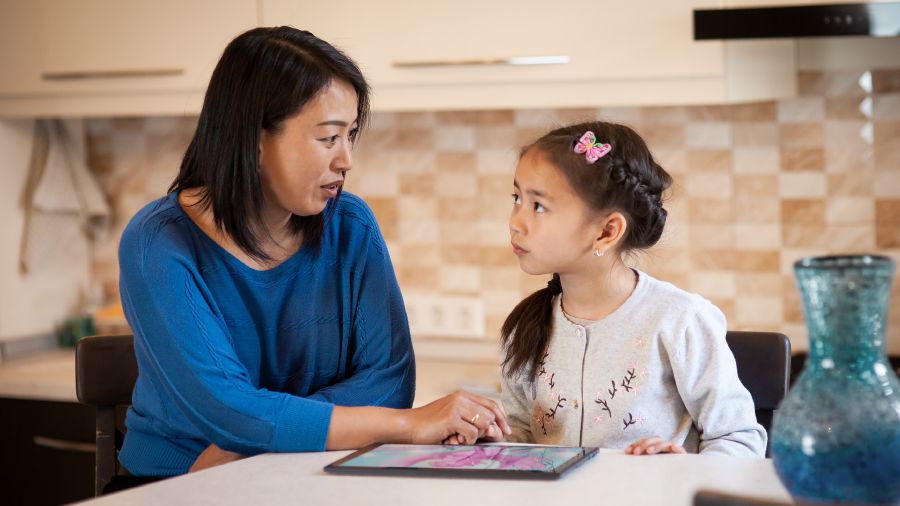 Una madre habla con su hija sobre ver cosas perjudiciales en su dispositivo electrónico