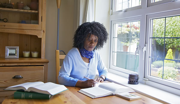 Rosalind John skriver notater og undersøger Bibelen nærmere ved hjælp af opslagsværker.