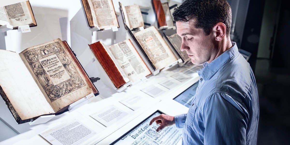 Ein Mann schaut sich in einem Museum alte Bibeln an
