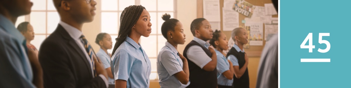 Lektion 45. Während in der Schule die Nationalhymne gesungen wird, steht eine junge Schwester respektvoll zwischen den Mitschülern; allerdings ohne mitzusingen oder die Hand aufs Herz zu legen.