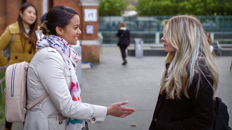 Eine Szene aus dem Video „Erlebe die Freude, Jünger zu machen – Werde ein besserer Bibellehrer: Fragen stellen“. Nisha streckt ihre Hand aus, um Lottes Hand zu schütteln, und stellt sich ihr vor.