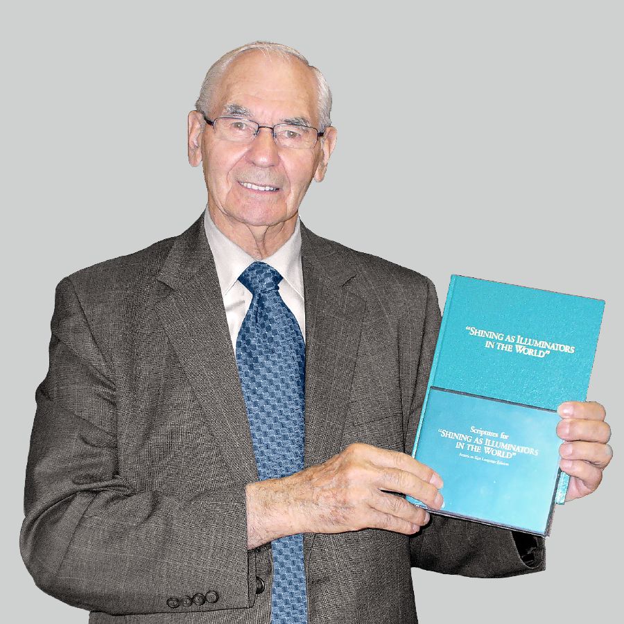 Walter Markin im Alter von 79 Jahren mit seinem Pionierschulbuch und einer DVD in Gebärdensprache in den Händen