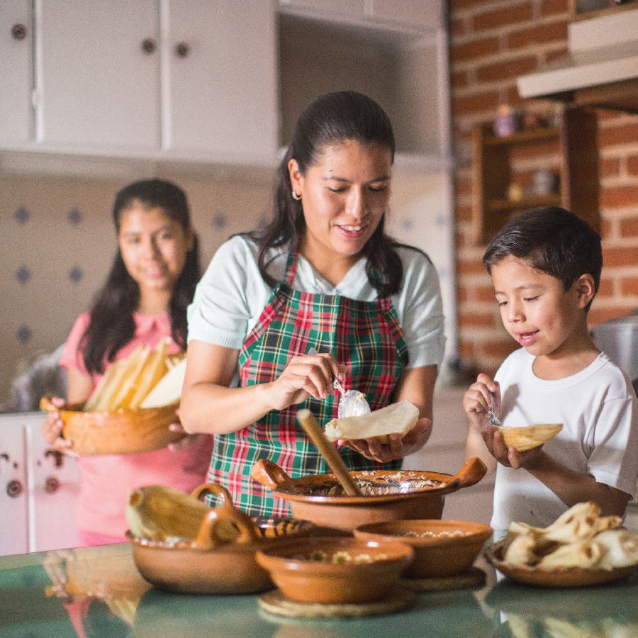 Eine Mutter kocht mit ihren Kindern für ihre Gäste