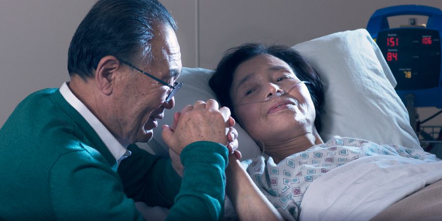 Αδελφός προσεύχεται μαζί με τη γυναίκα του η οποία βρίσκεται σε κρεβάτι νοσοκομείου