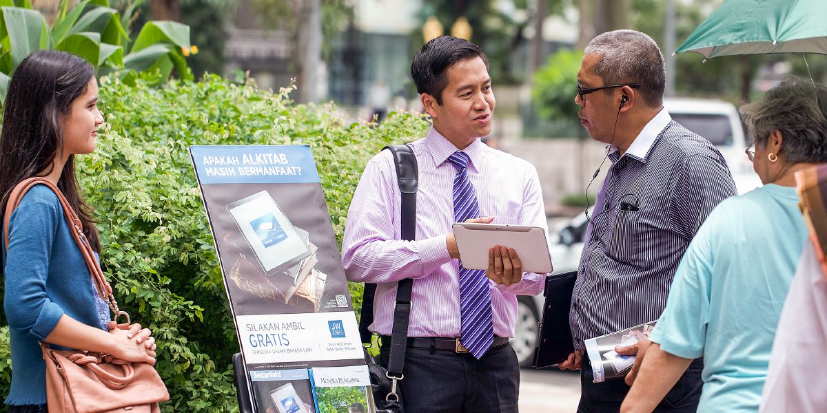 Μάρτυρες του Ιεχωβά στέκονται δίπλα σε σταντ δημόσιας μαρτυρίας στην Ινδονησία και κηρύττουν στους ανθρώπους