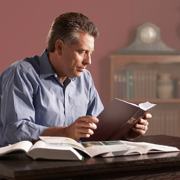 A brother reading the Bible. There are Bible-based publications laying open on his desk.