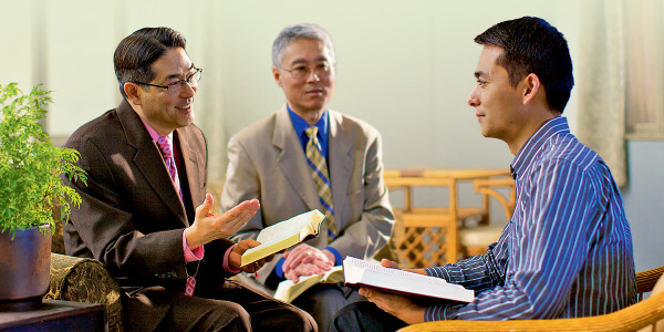 Two elders using the Bible to reason with a brother.
