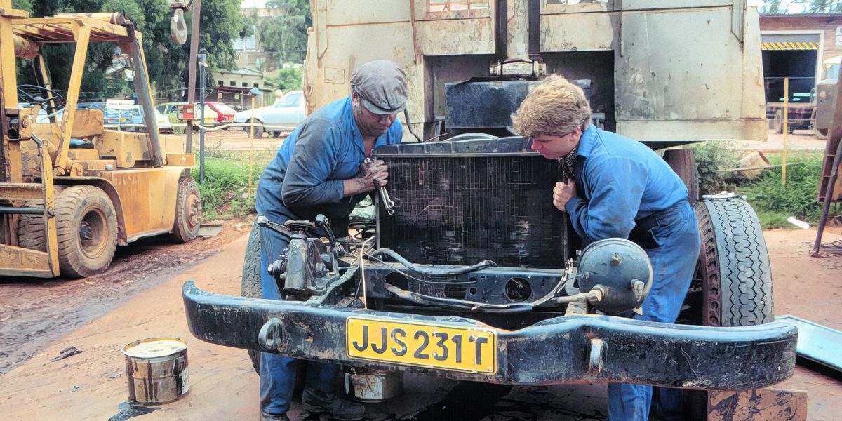 A white brother and a black brother repair a vehicle together.