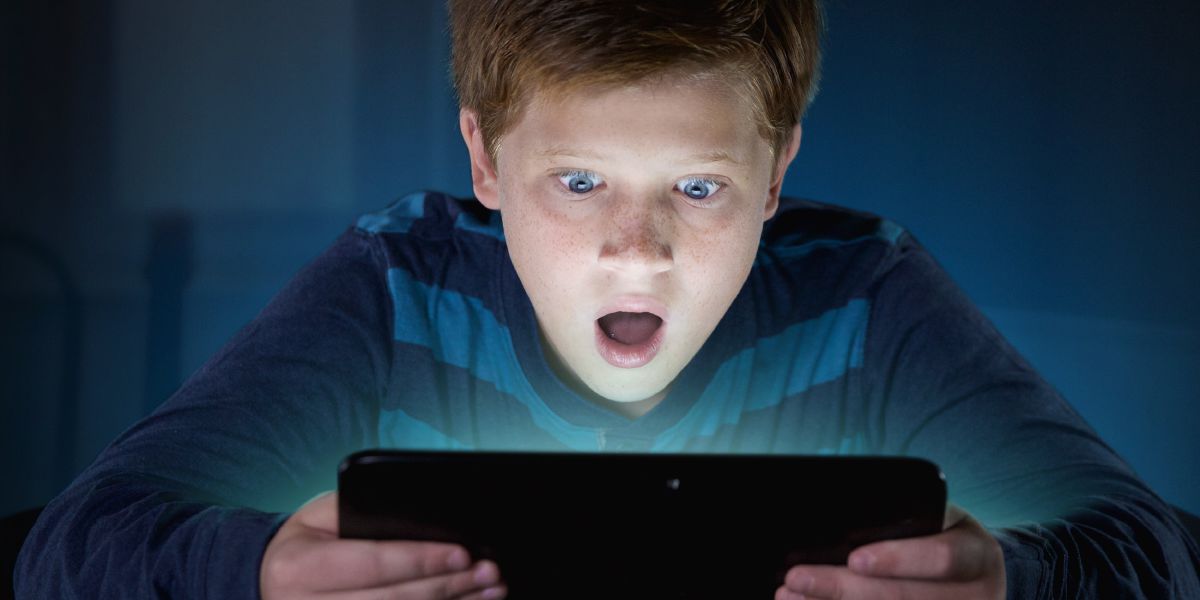A boy is astonished by what he sees on his electronic device