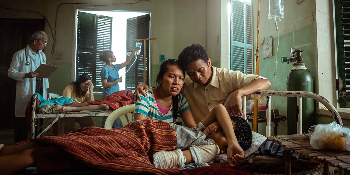 Parents watching as their young son lies in a hospital bed after having part of his arm amputated.