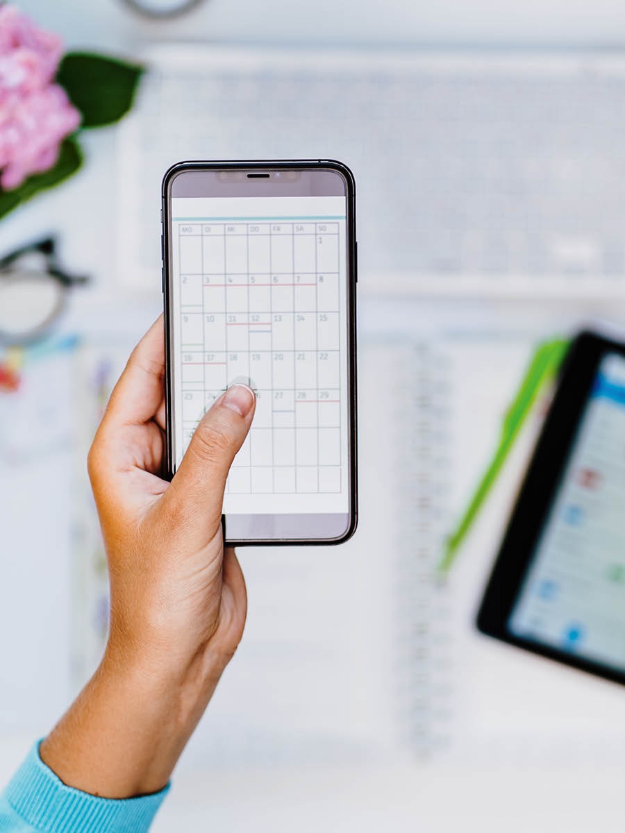 A woman holding her smartphone, using a daily planning application.