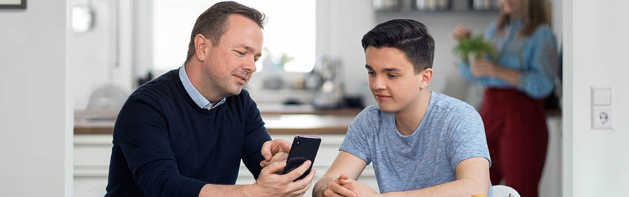 A father teaching his son how to use a smartphone responsibly.