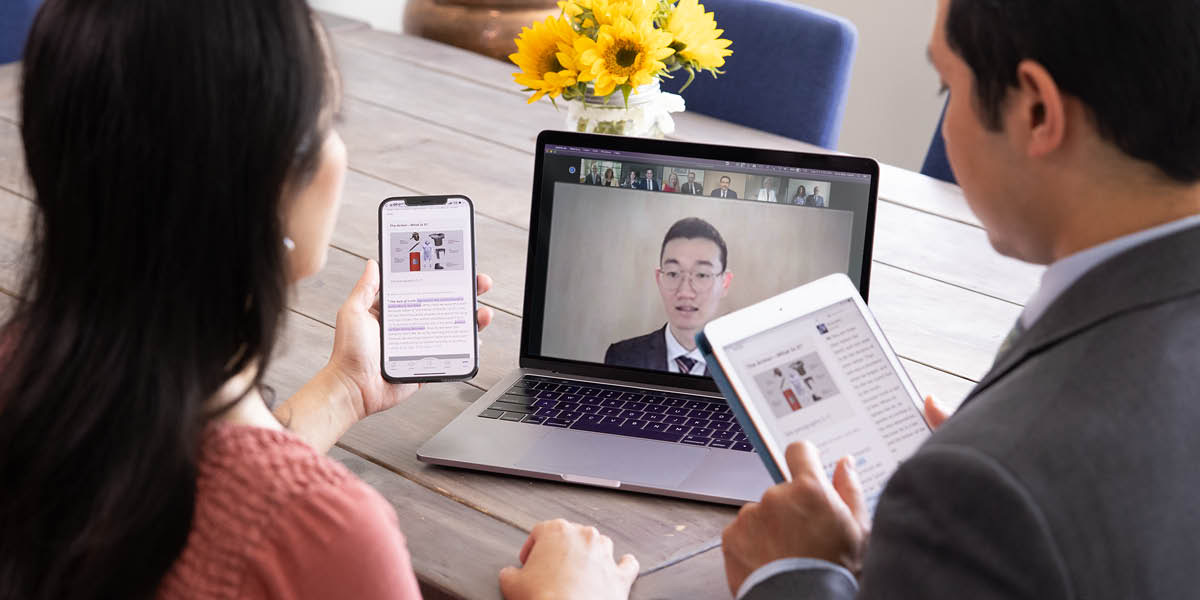 A couple attending a congregation meeting via videoconferencing while using the “JW Library” app on their electronic devices.