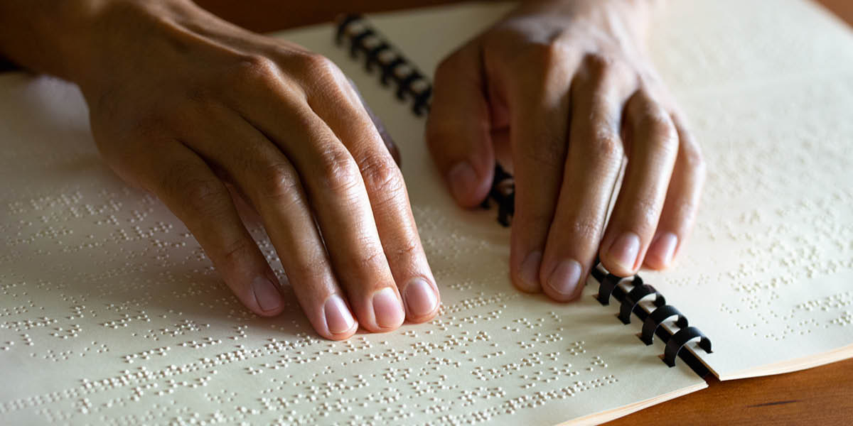 A blind woman using her fingers to read a braille publication.