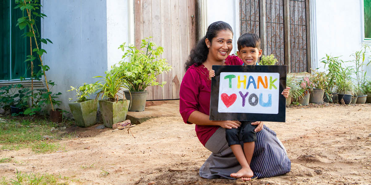Imara with her son Enosh. He holds a sign that reads: ‘thank you.’