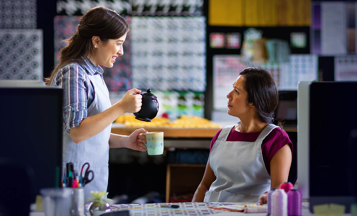 The woman shown earlier kindly offering a cup of tea to her surprised coworker.