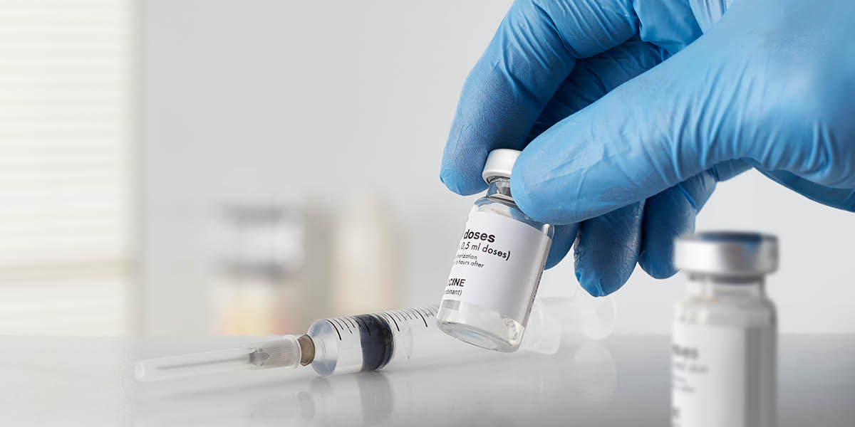 Vaccination materials including a hypodermic syringe and vaccine bottles.