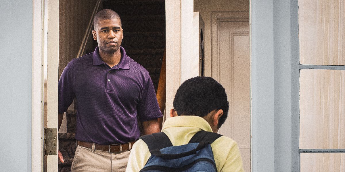 A father opens the door and his son walks into the house, holding his head down