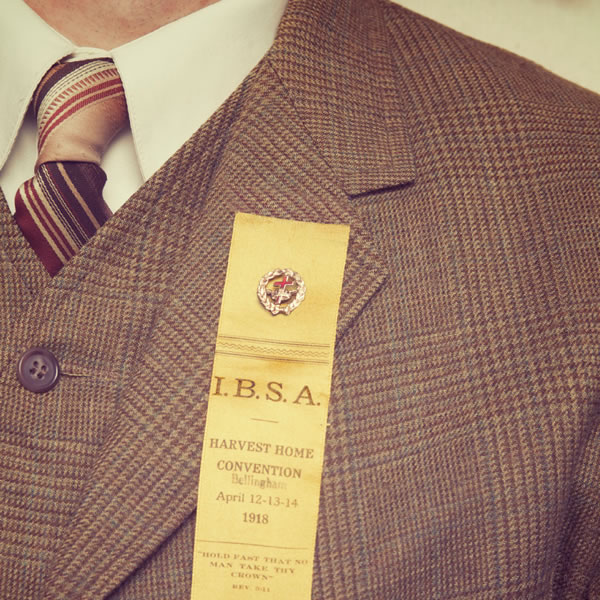 A man wearing a cross-and-crown pin on his jacket lapel