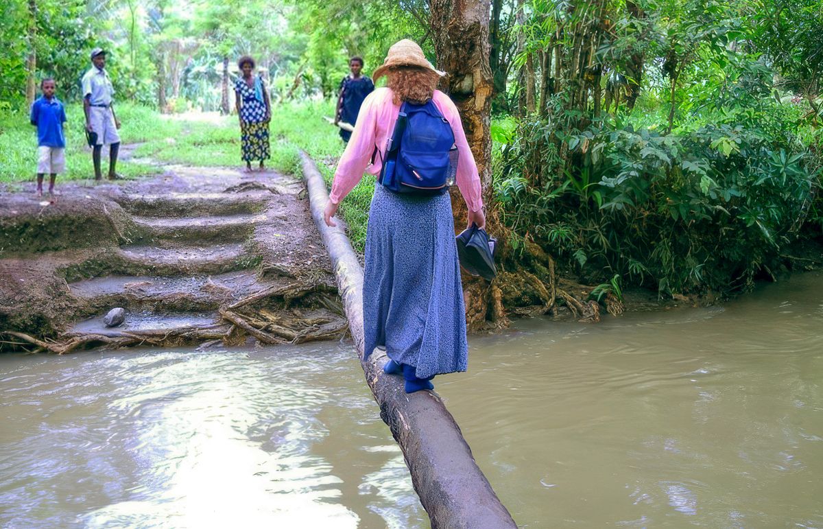 Leann walking across a narrow log to cross a river.