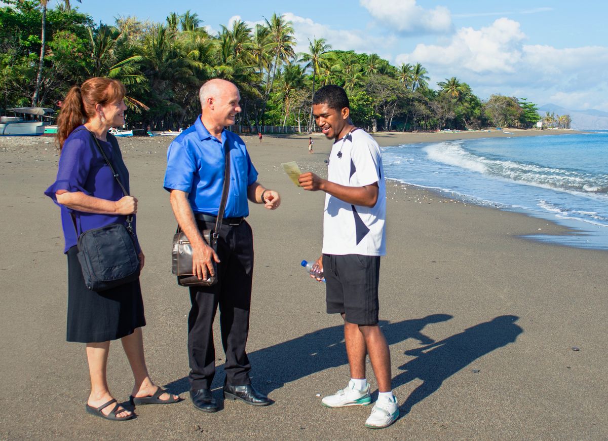 Warren and Leann preaching to a man on a beach.
