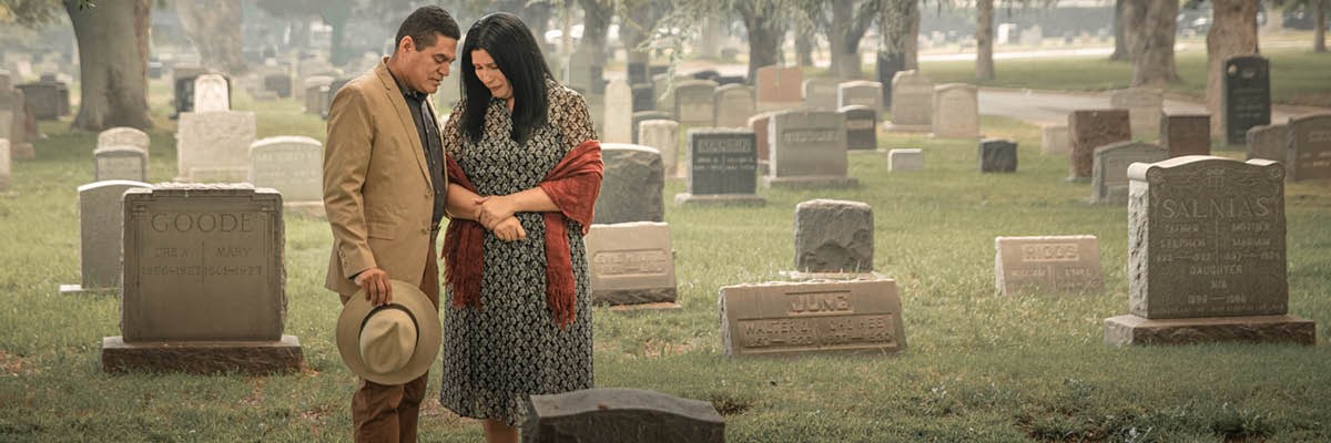 A couple grieving in a cemetery.