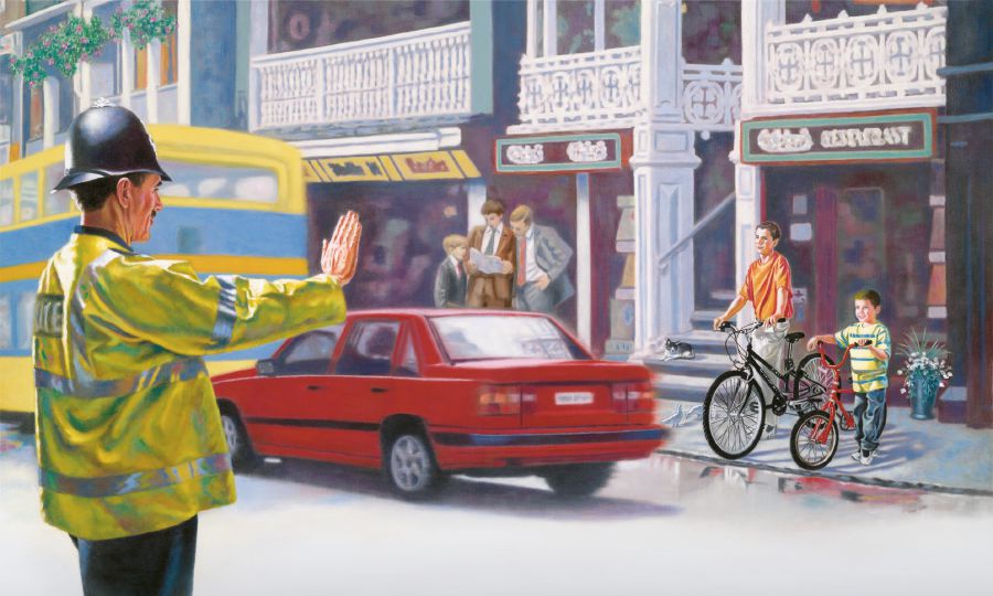 A policeman tells boys to wait before crossing a street