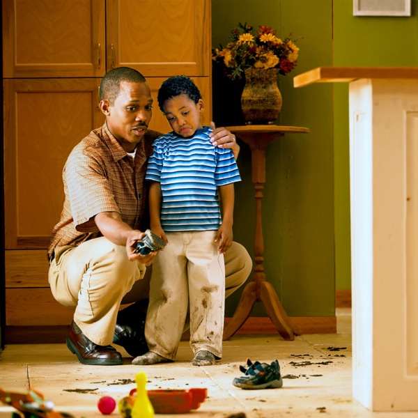 A father lovingly corrects his son who has brought mud into the house