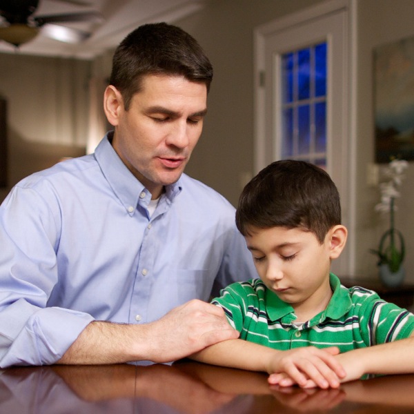 A loving father prays with his son