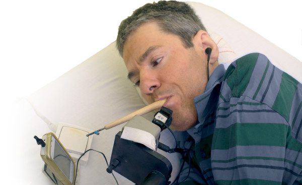 Félix Alarcón holds a rod in his mouth and dials numbers on a cell phone