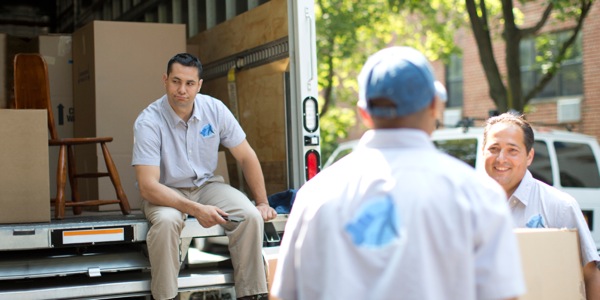 A frustrated young man sitting down while his moving crew continues working