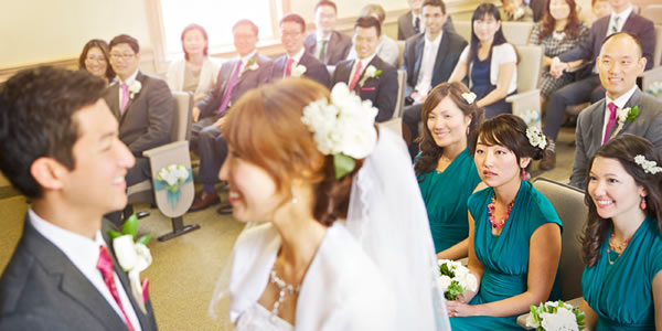 A bride and groom exchange marriage vows, as others in the congregation look on