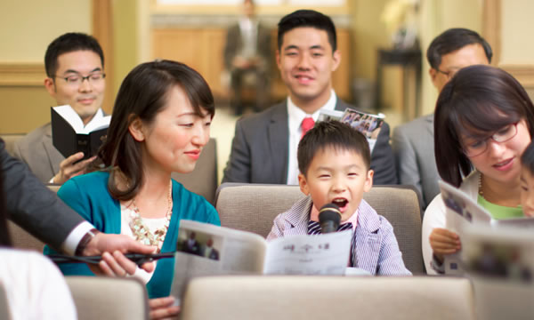 A sister helps a little boy give a comment at the meeting