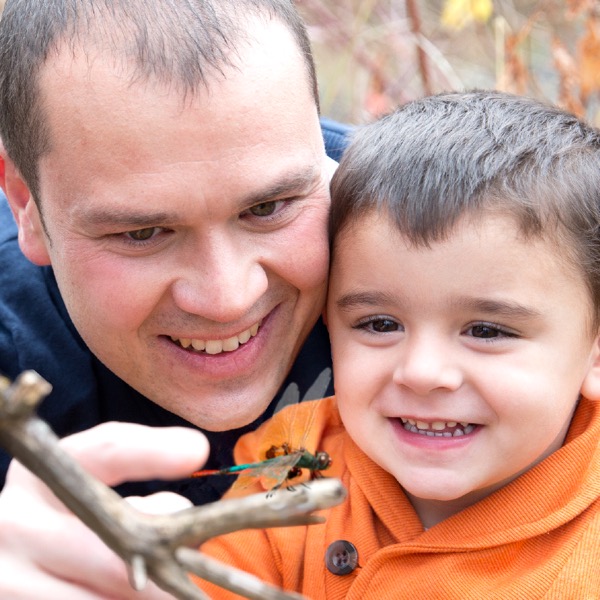 A father and son looking at a dragonfly