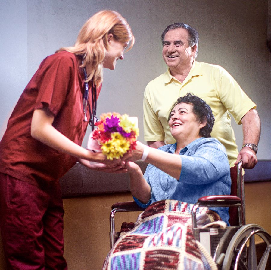 A couple give a health-care worker a bouquet of flowers