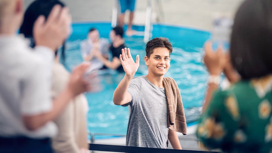 A young man waves to his family and friends before going into a baptismal pool