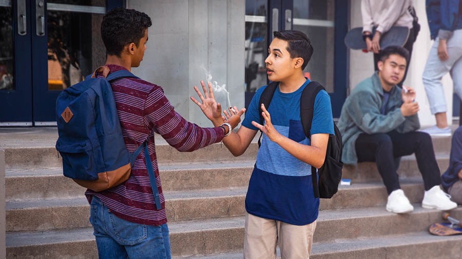 A young brother rejecting a cigarette that is offered by a schoolmate.