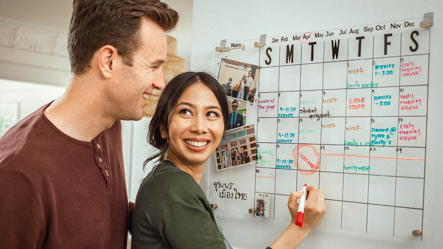 The couple writing down their spiritual goals on a wall calendar.