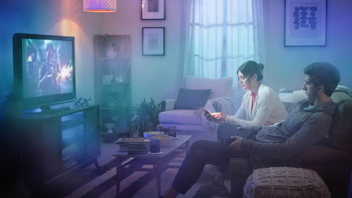 A brother watches a violent movie while his wife sits next to him, doing something on her phone. The Bible on their coffee table is covered up with secular magazines.
